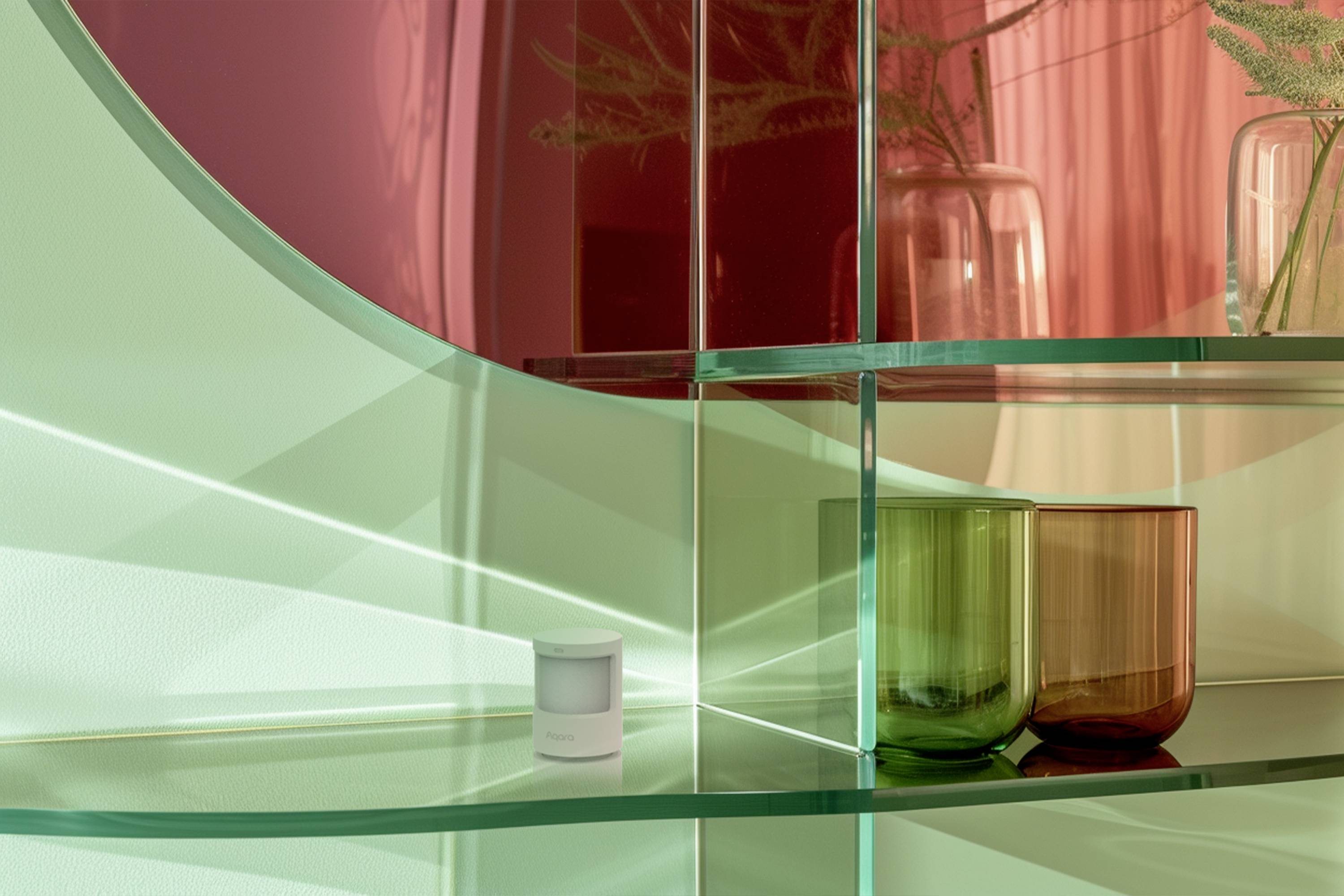 Bicchieri verdi e rossi su uno scaffale di vetro con riflessi di luce. Disposizione decorativa in un ambiente moderno.