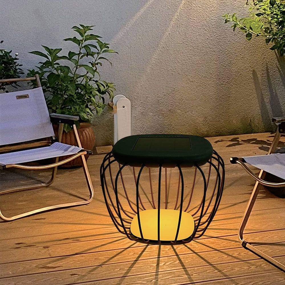 Scena notturna su una terrazza con due sedie, piante e un tavolo illuminato che emana una luce calda e accogliente.