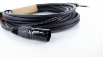 Un cavo audio nero con connettore XLR e jack, arrotolato. Adatto per trasmissioni audio in studio.