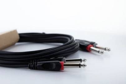 Un cavo jack audio con due connettori neri su uno sfondo bianco. Il cavo è adatto per collegare strumenti musicali.