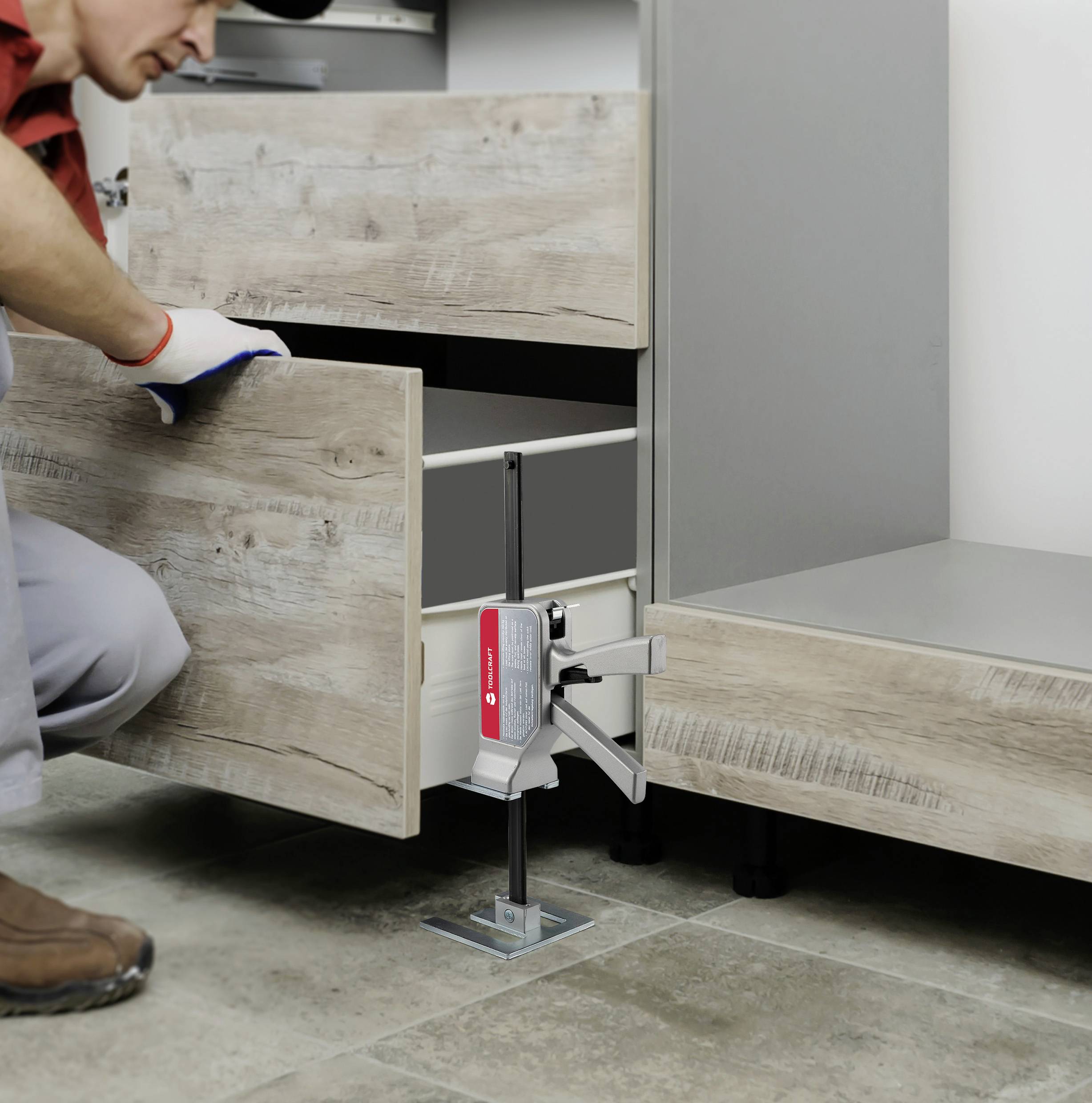 Una persona sta montando un cassetto in legno su un mobile da cucina utilizzando un attrezzo speciale per la stabilizzazione e la regolazione precisa.
