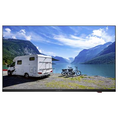 Un camper è parcheggiato accanto a un lago pittoresco circondato da montagne. Due biciclette sono parcheggiate accanto, pronte per un'escursione nella natura.