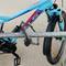 Una bicicletta blu è assicurata con un lucchetto a combinazione a un supporto metallico. La ruota anteriore ha catarifrangenti arancioni.