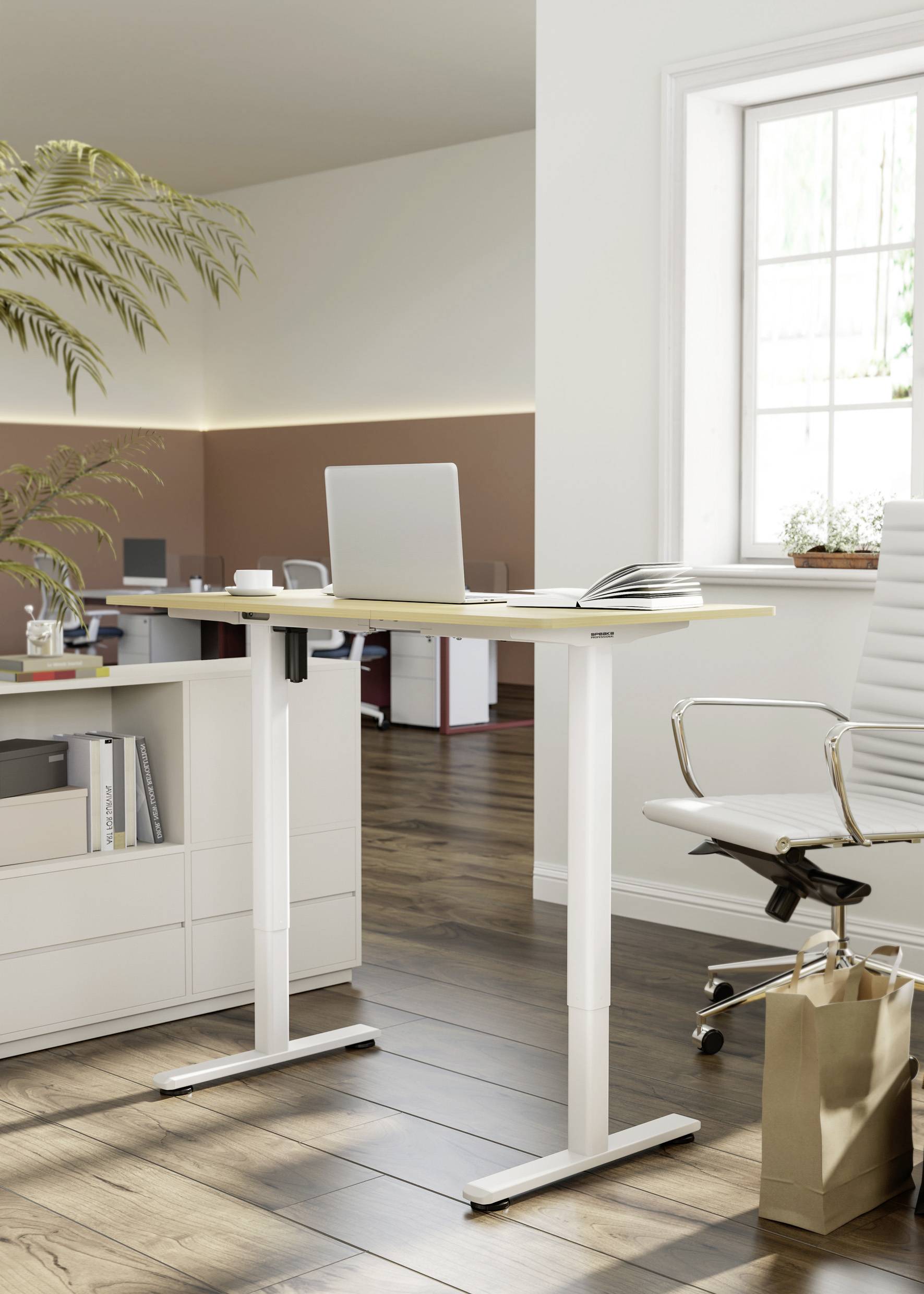 Un tavolo da lavoro regolabile in altezza con un laptop e un quaderno in un ufficio moderno, accanto a una sedia da ufficio bianca e una pianta.