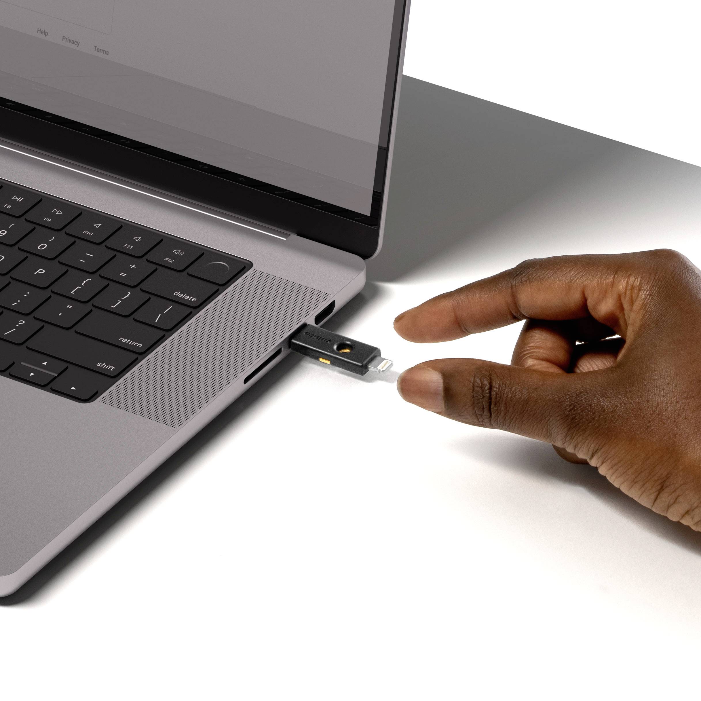 Una persona inserisce una chiavetta USB in un laptop. Il laptop è aperto e acceso. La mano tiene saldamente la chiavetta USB.
