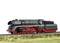 Un modello di locomotiva a vapore verde con ruote rosse su un binario, circondato da erba. La locomotiva ha un design dettagliato.
