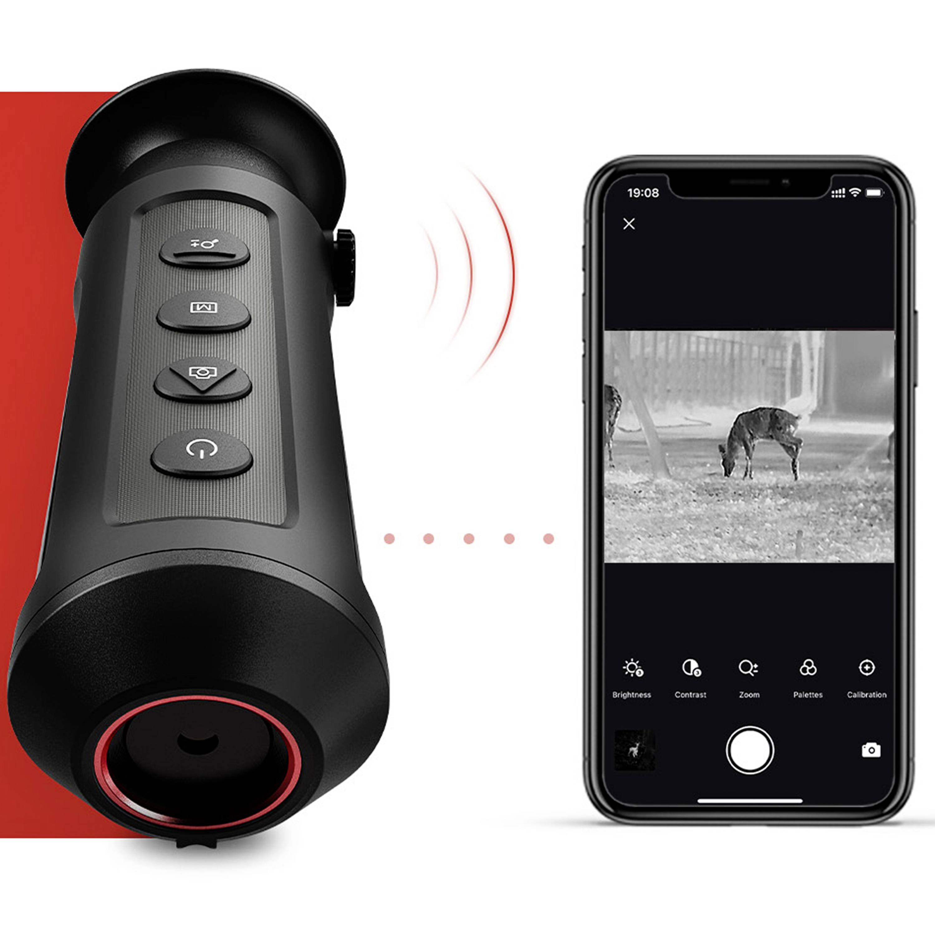 Dispositivo portatile per visione notturna accanto a uno smartphone che mostra un'immagine in bianco e nero di un animale durante la notte.