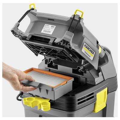 Aspirapolvere industriale con coperchio aperto, persona che sta cambiando il filtro. Dispositivo nei colori grigio e giallo, nome del marchio visibile.