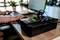 Una persona sta lavorando su un laptop, mentre in primo piano è presente un dispositivo con diversi cavi su un tavolo.