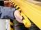 Una persona sta fissando un nastro di avvertimento giallo e nero su un bordo di uno scaffale come misura di protezione e sicurezza.