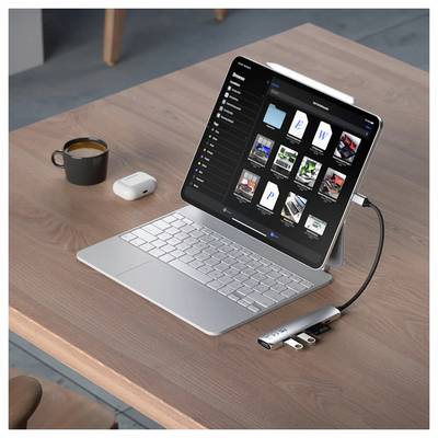 Un tablet con una tastiera è posizionato su un tavolo di legno. Mostra la gestione dei file. Accanto a esso ci sono una tazza, degli AirPods e un dongle.