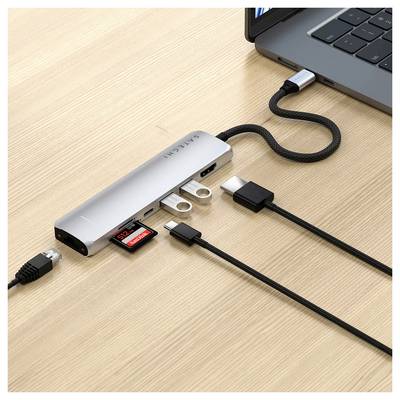 Un laptop è collegato a un hub USB-C che offre diversi porte, tra cui HDMI, USB e lettore di schede. Su un tavolo di legno.