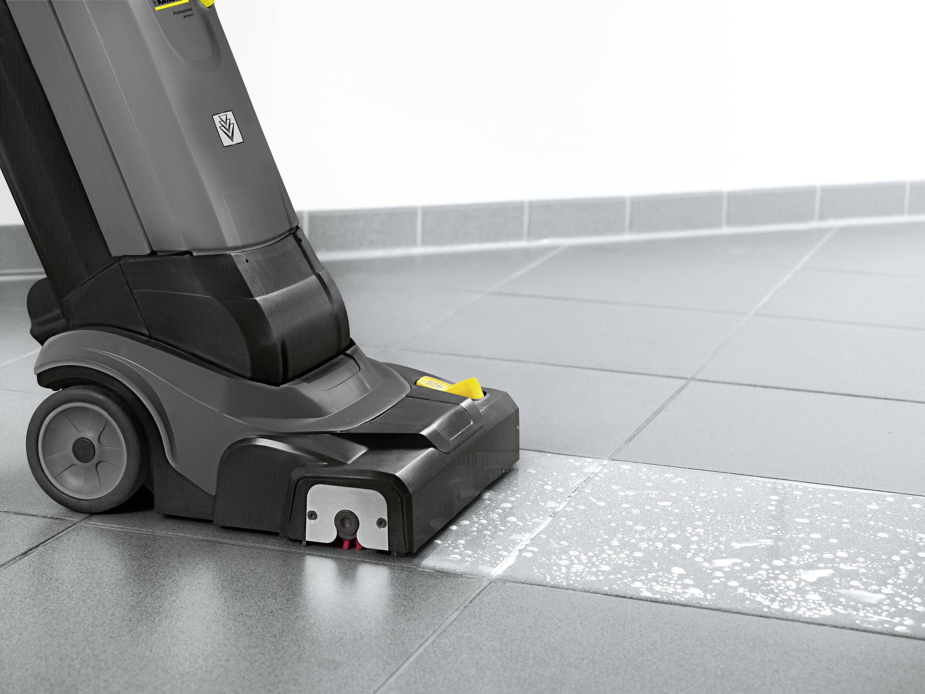 Un dispositivo per la pulizia dei pavimenti sta pulendo una superficie piastrellata con acqua e sapone. Il pavimento appare parzialmente pulito e parzialmente sporco.