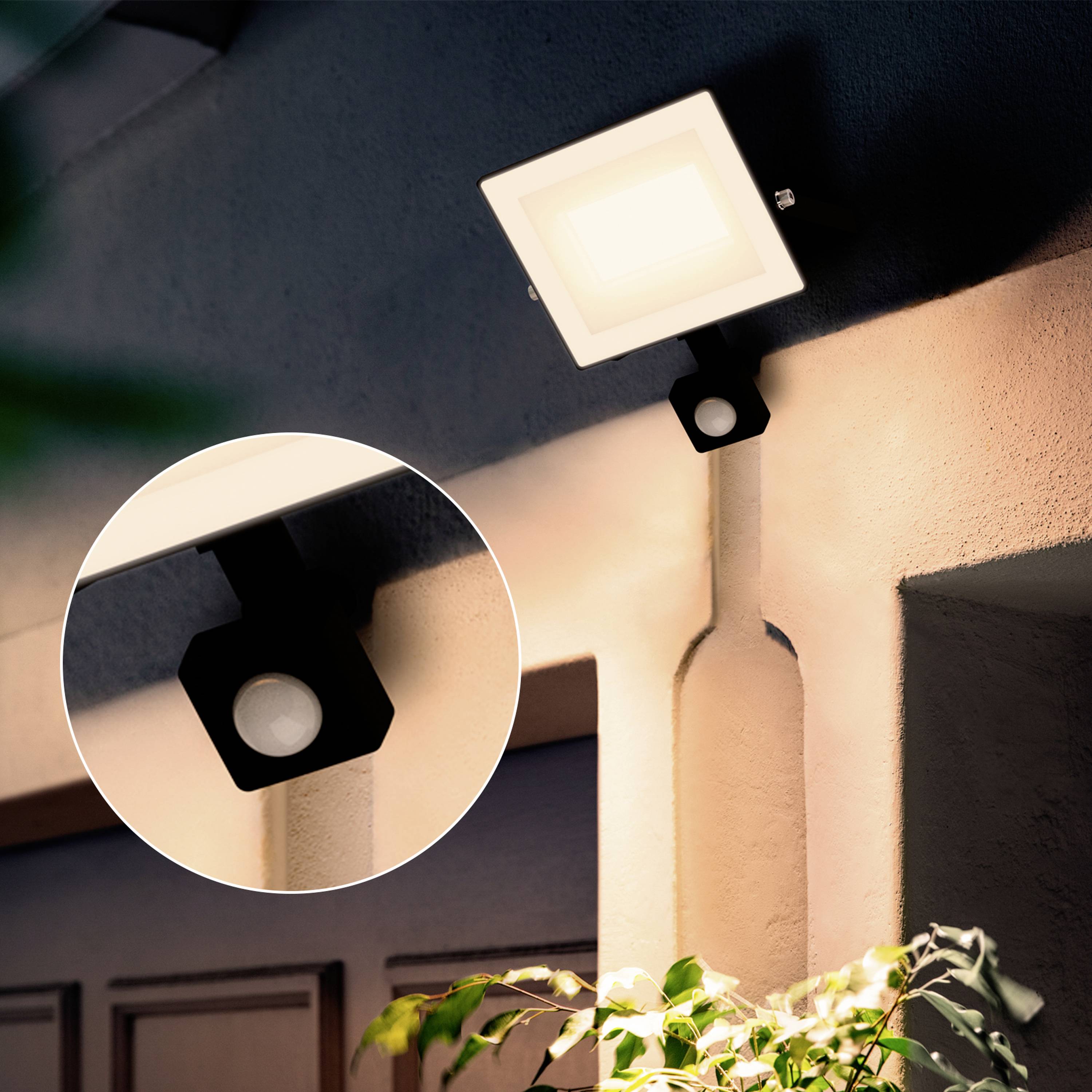 Lampada esterna montata su un muro esterno che illumina un'area chiara. Un'immagine ingrandita mostra la forma quadrata e la luce della lampada.