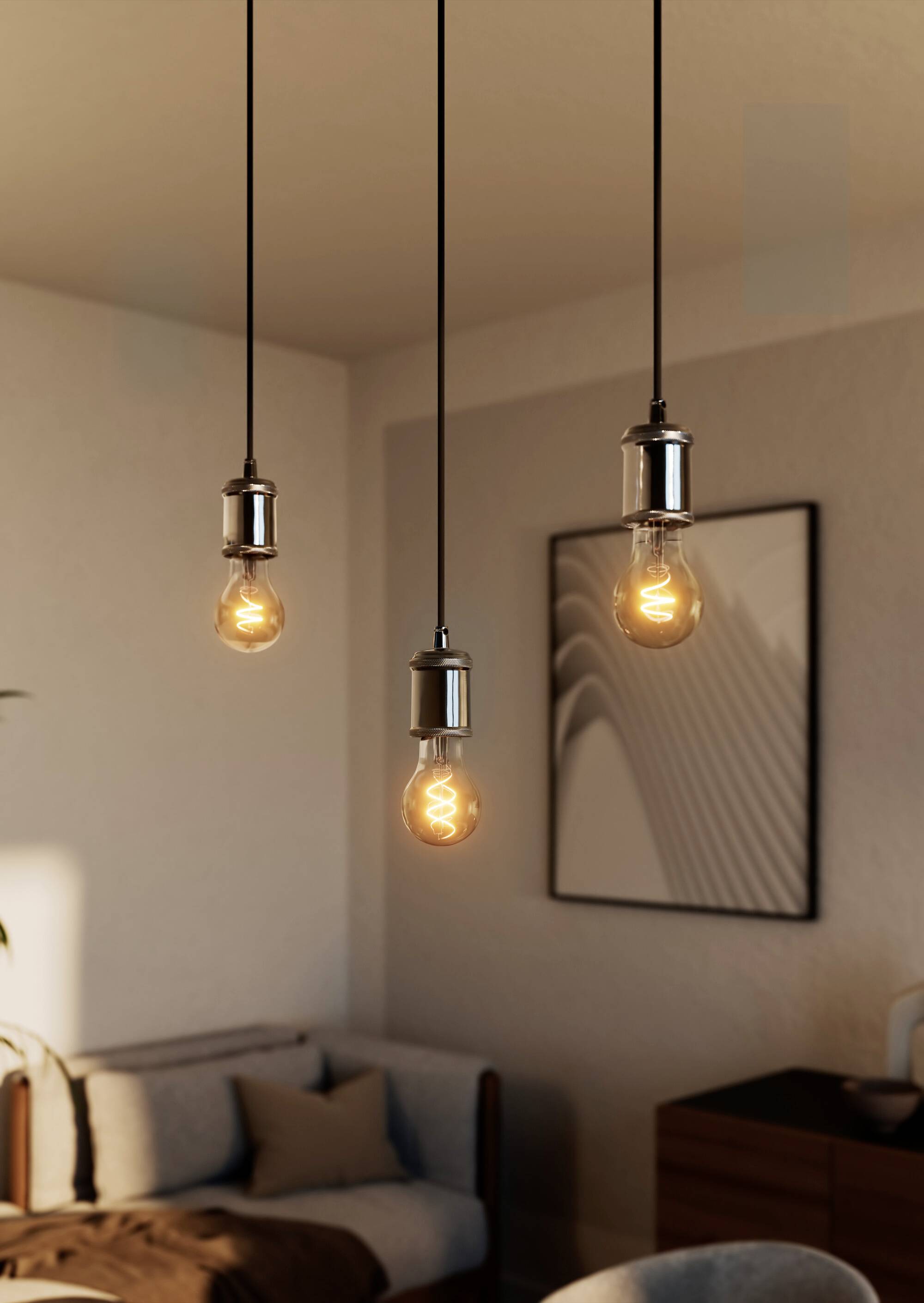Tre lampadine a sospensione illuminano un soggiorno moderno con mobili in legno e un'opera d'arte astratta appesa alla parete.