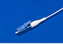 Un connettore in fibra ottica blu e bianco giace su uno sfondo blu.