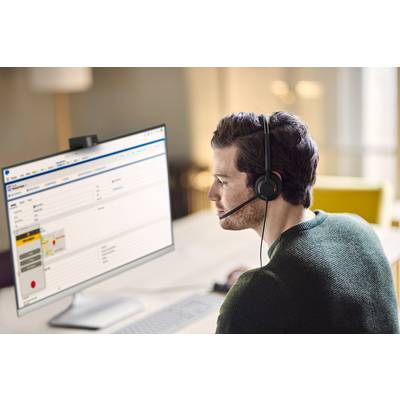 Un uomo con un headset è seduto a una scrivania e guarda uno schermo del computer su cui è visualizzato un software per il servizio clienti.