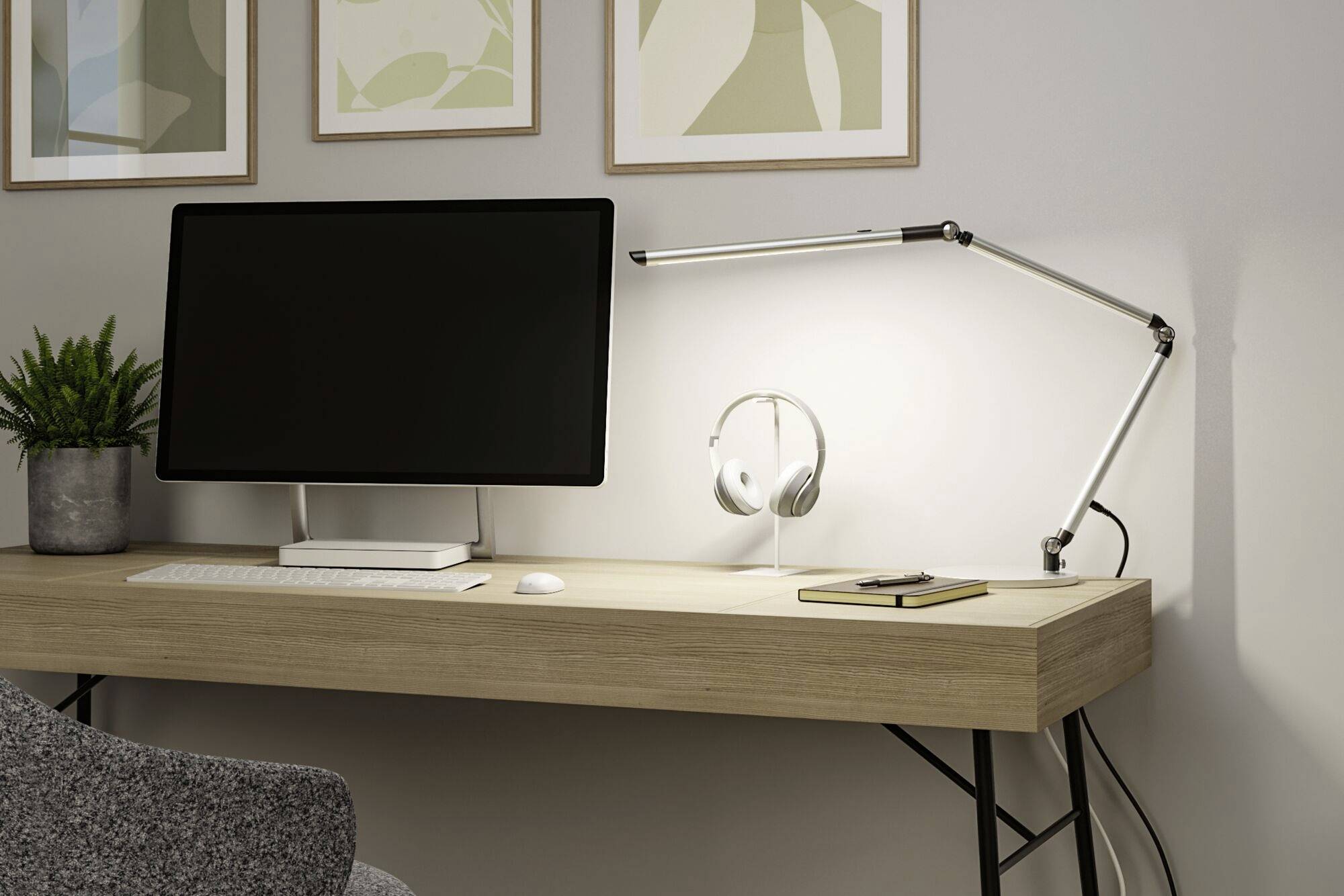 Scrivania moderna con computer, lampada da scrivania, cuffie e pianta. Ambiente di lavoro minimalista e funzionale.