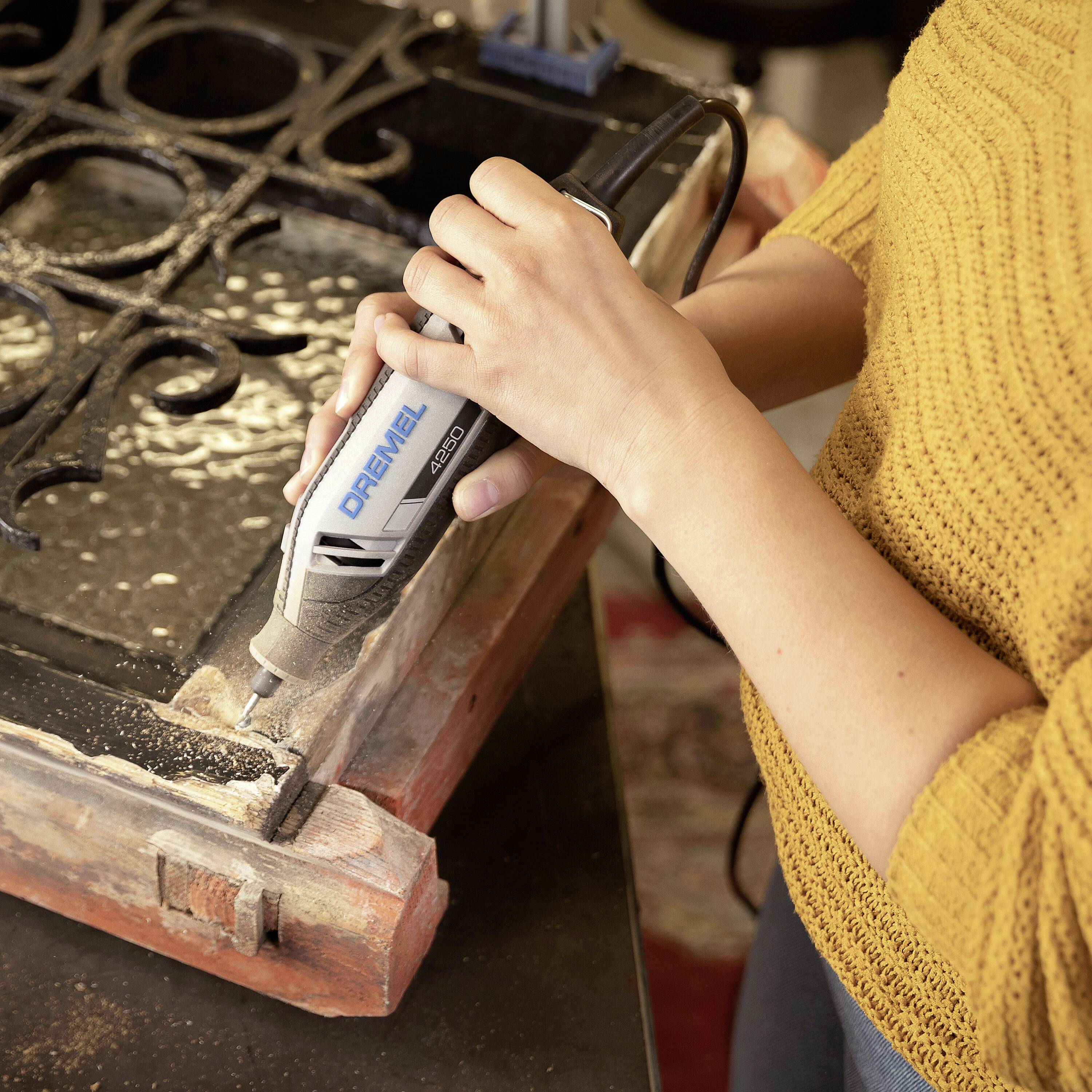 Una persona sta lavorando con un utensile Dremel su una cornice di legno per ritagliare dei dettagli.