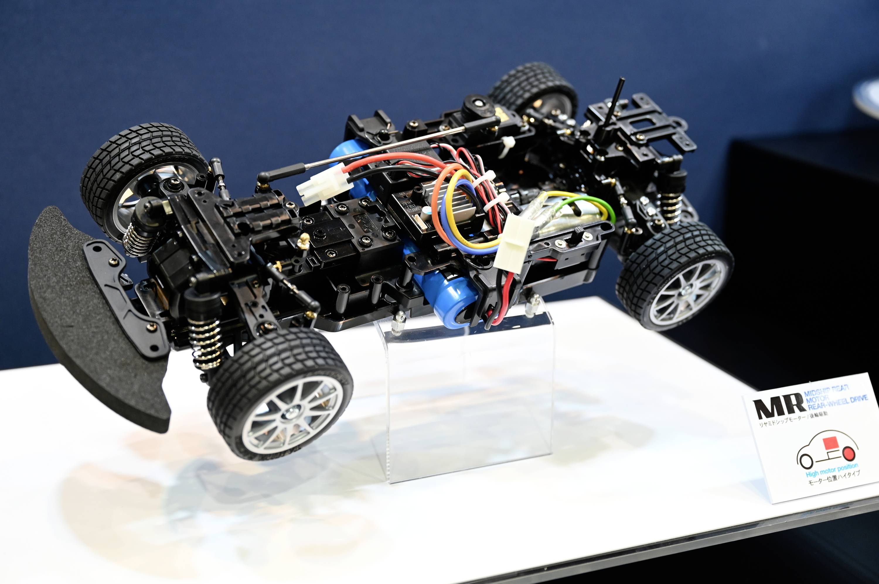 Telaio RC-Auto nei dettagli: sospensione, elettronica e cablaggi ben visibili. Cornice di presentazione con piccolo diagramma a lato.