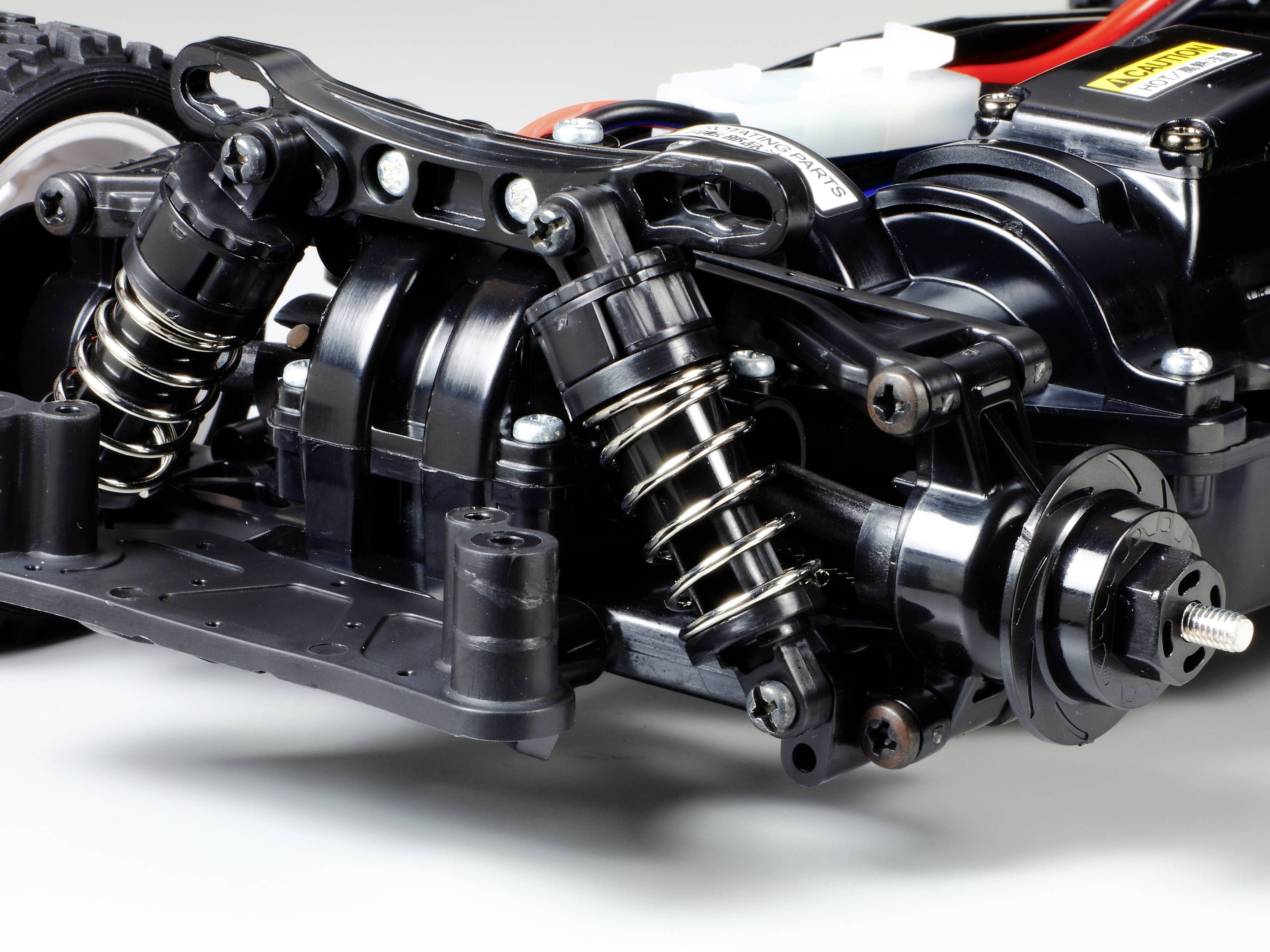 Primo piano di un sistema di sospensione per auto radiocomandata con ammortizzatori ed elementi di sospensione, che mostra dettagli tecnici e configurazione costruttiva.