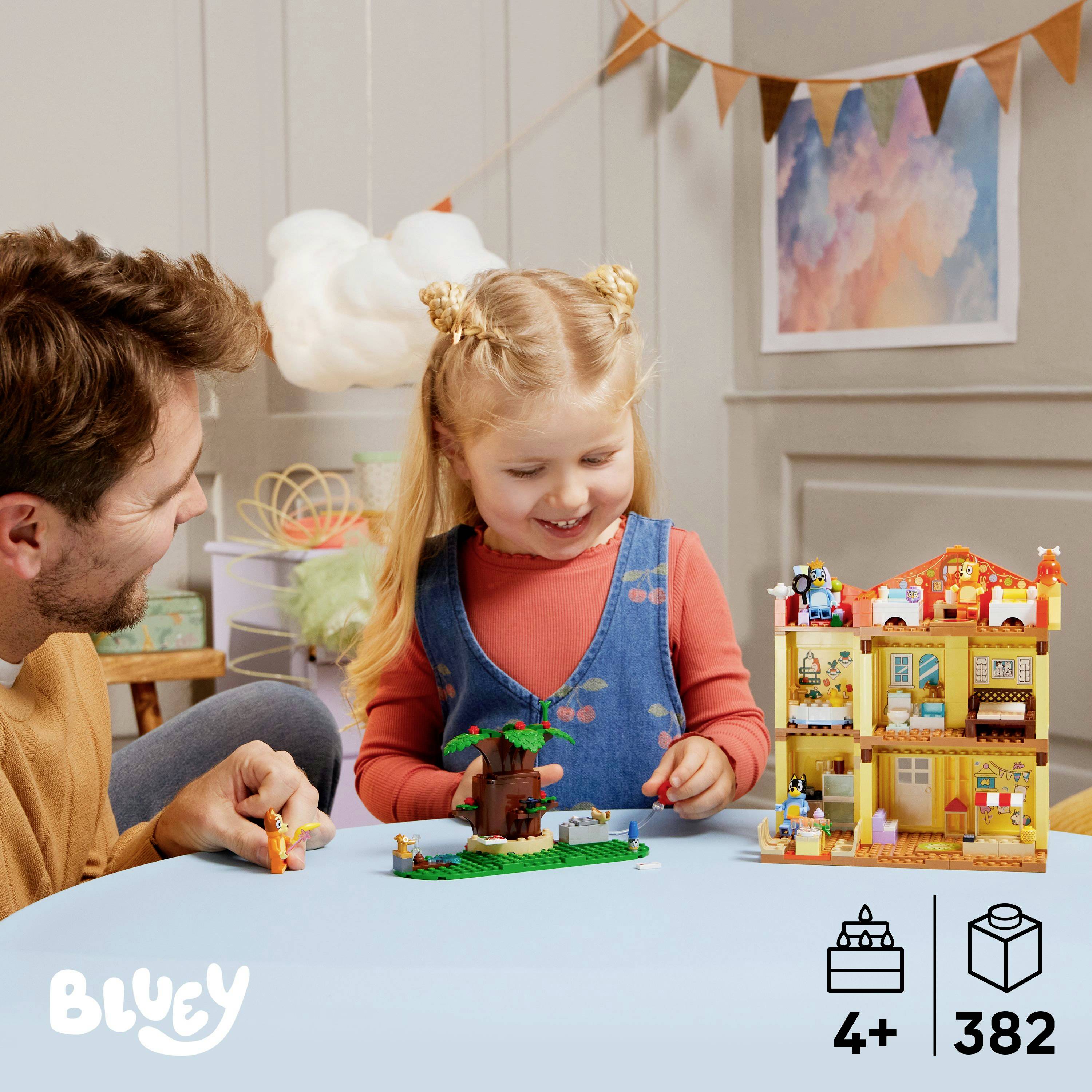 Un genitore e un bambino giocano con giocattoli da costruzione a tema Bluey su un tavolo. La scena suggerisce un gioco creativo e un momento di condivisione per bambini dai 4 anni in su, con 382 pezzi.