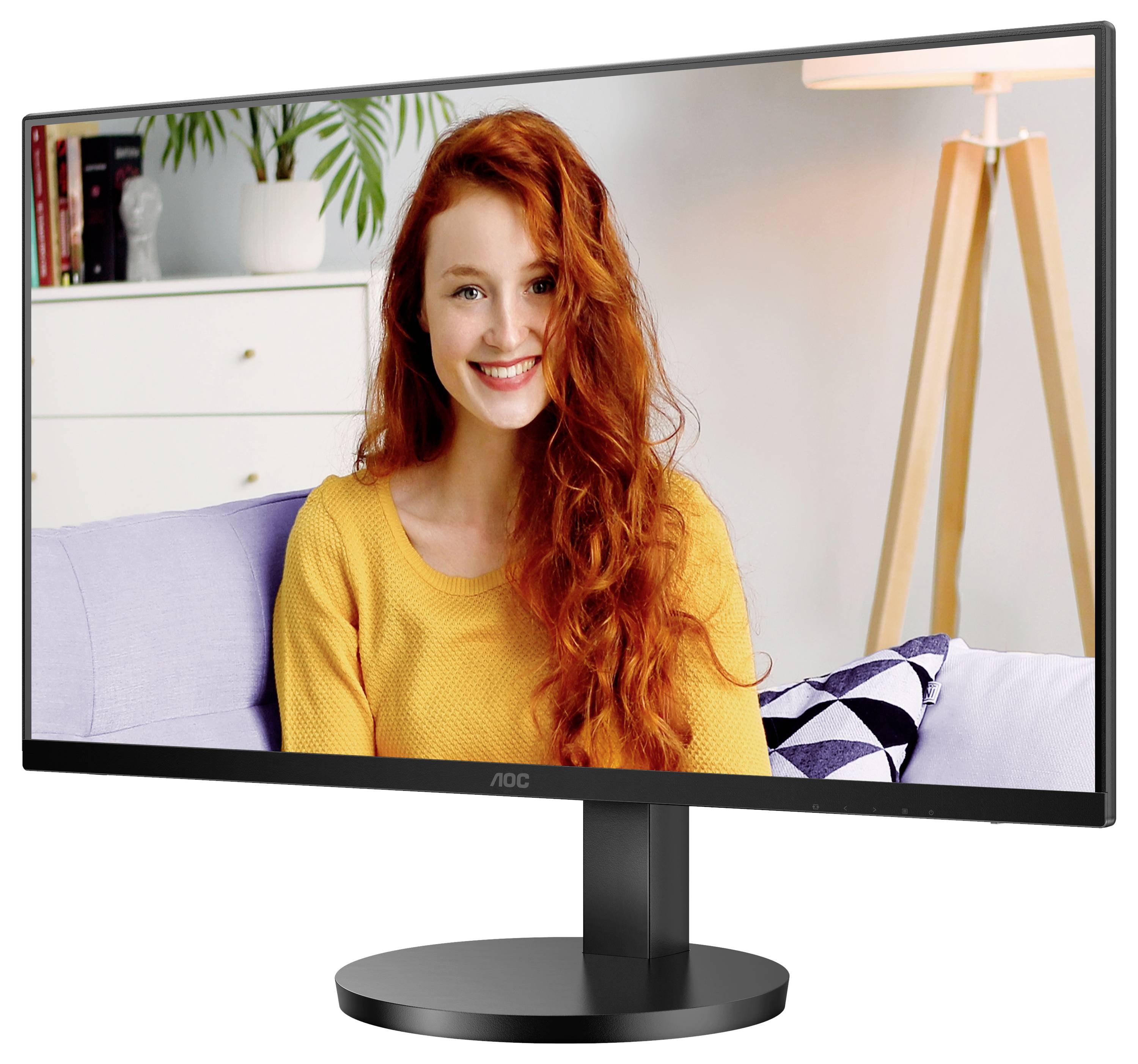 Una persona sorridente con lunghi capelli rossi è seduta su un divano in un soggiorno visualizzato su uno schermo di computer.