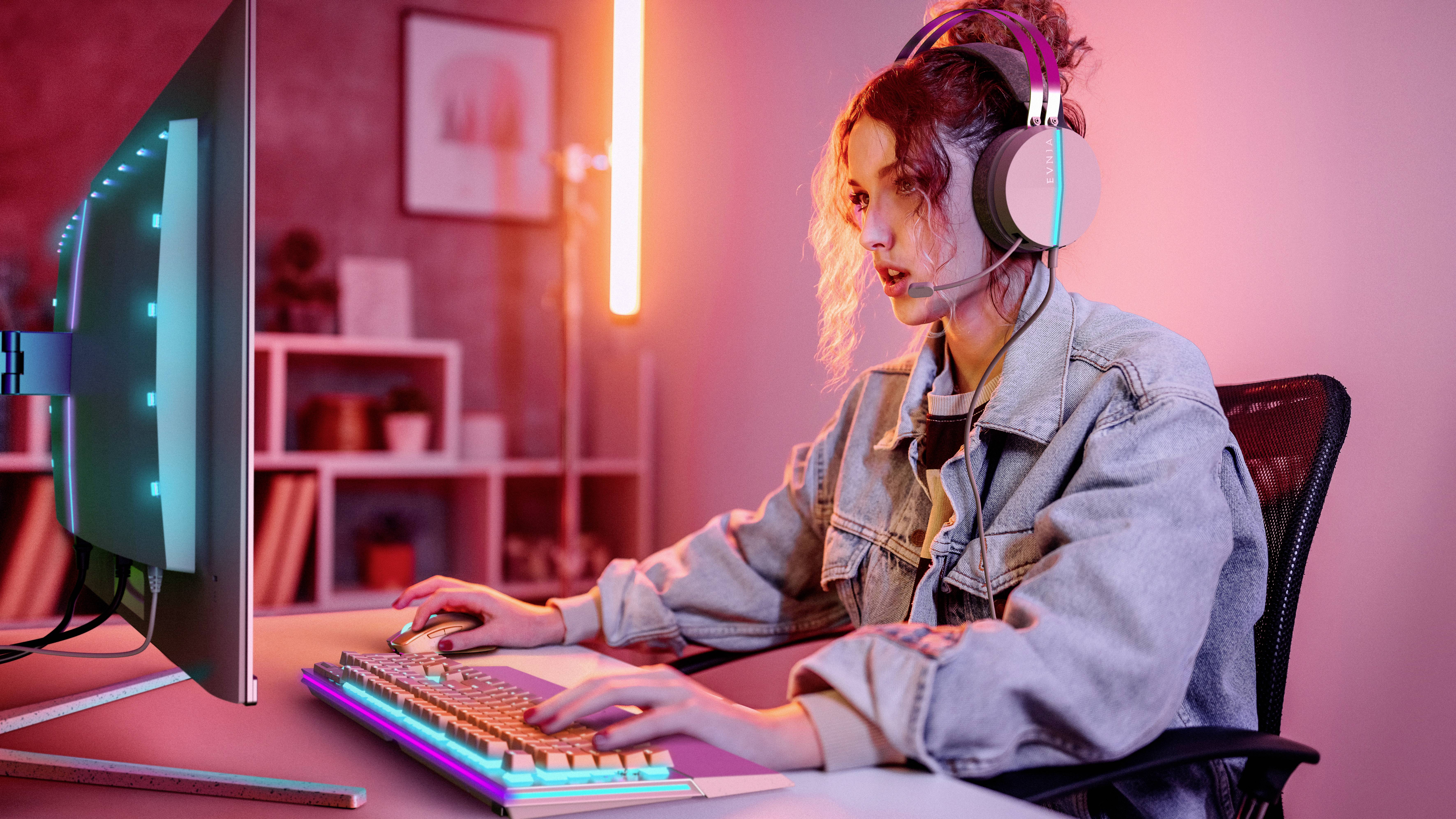 Una persona gioca concentrata al computer, indossando un headset. La stanza ha un'illuminazione soffusa con accenti rosa e blu.