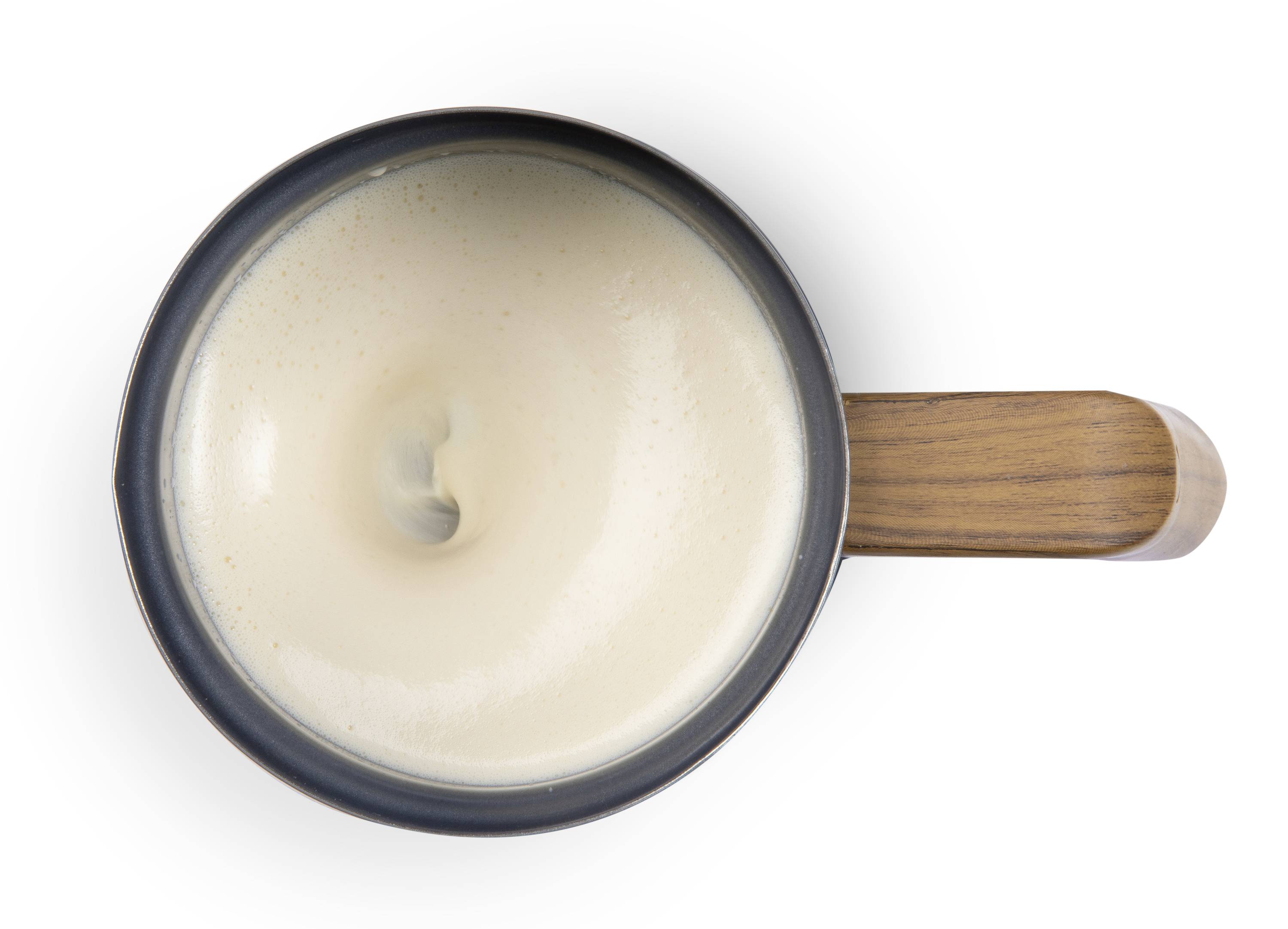 Una tazza di caffè nero con un vortice di schiuma, vista dall'alto, con un manico in legno a destra.