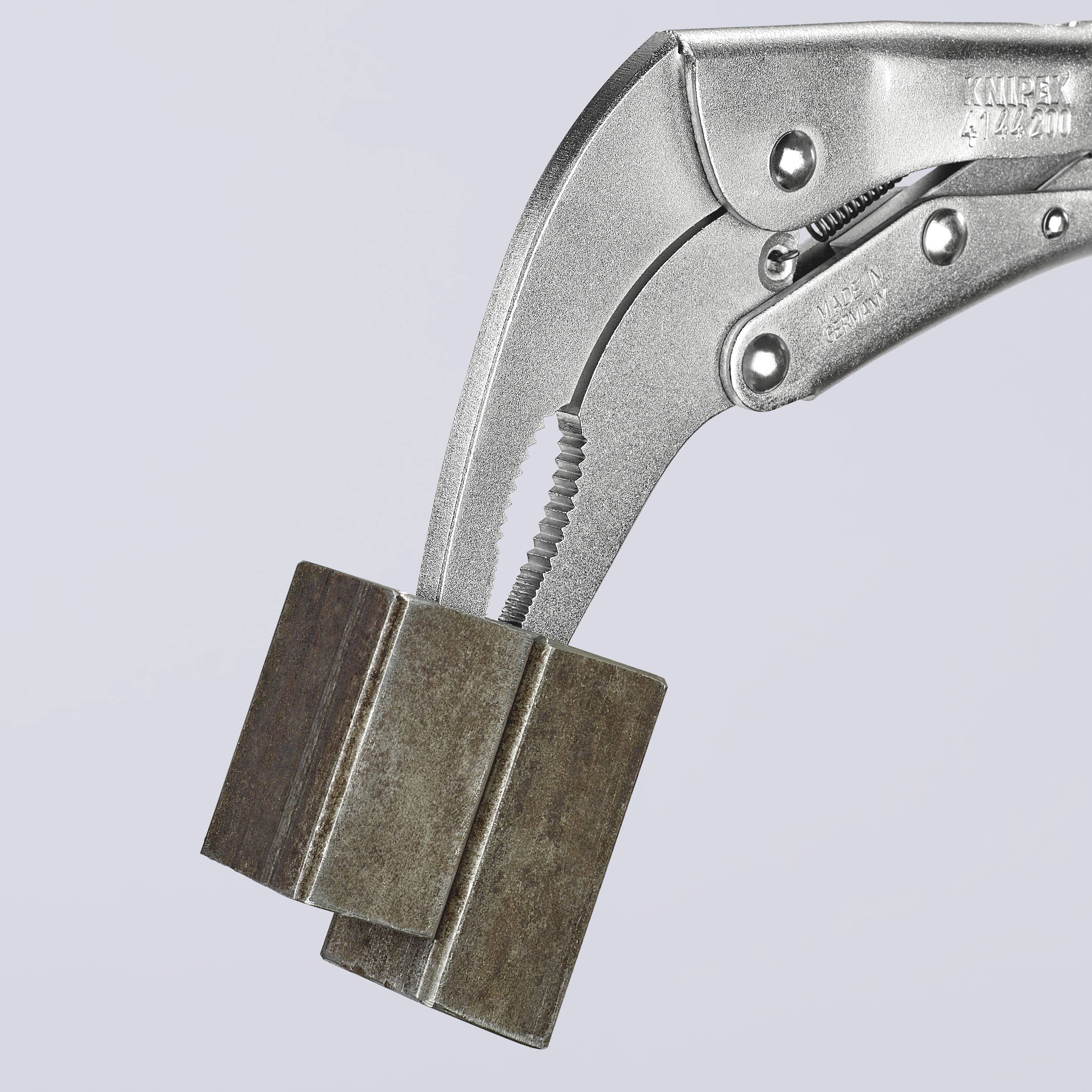 Una pinza a morsetto tiene un pezzo di metallo rettangolare. La pinza ha una superficie argentata ed è posizionata su uno sfondo neutro.