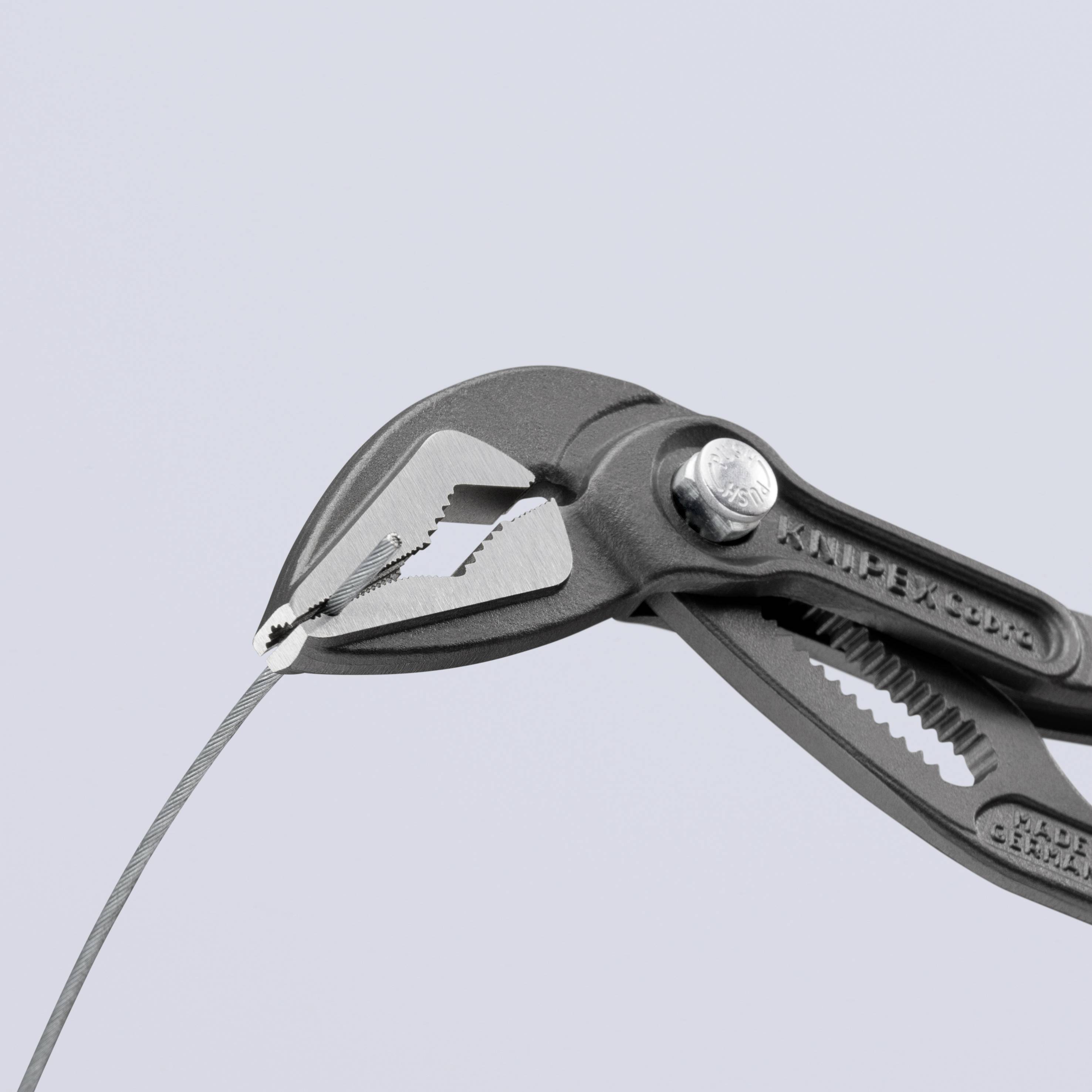 Primo piano di una pinza nera che afferra un sottile cavo metallico, sullo sfondo neutro.