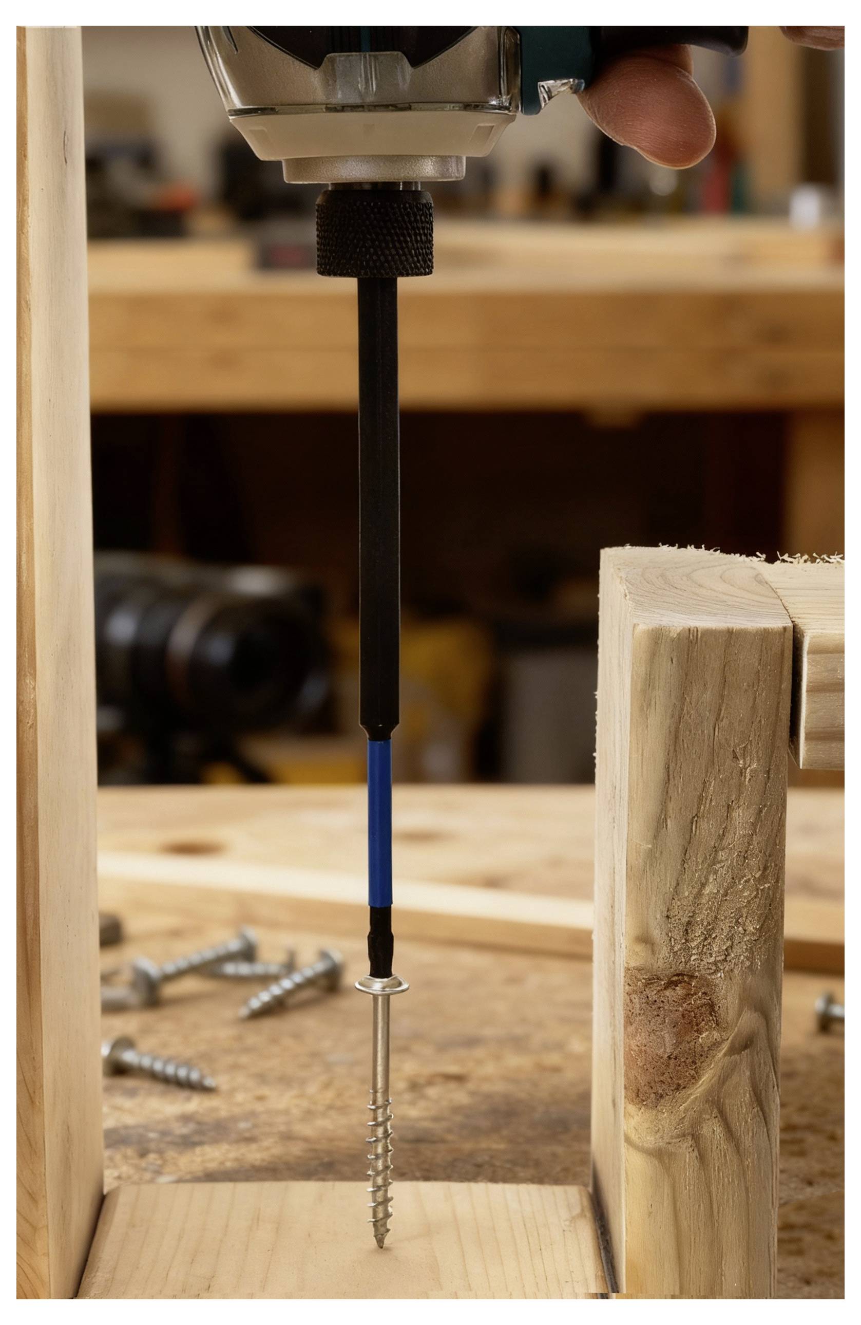 Un cacciavite che avvita una lunga vite in una tavola di legno, circondato da altre viti su un banco da lavoro in un ambiente di officina.