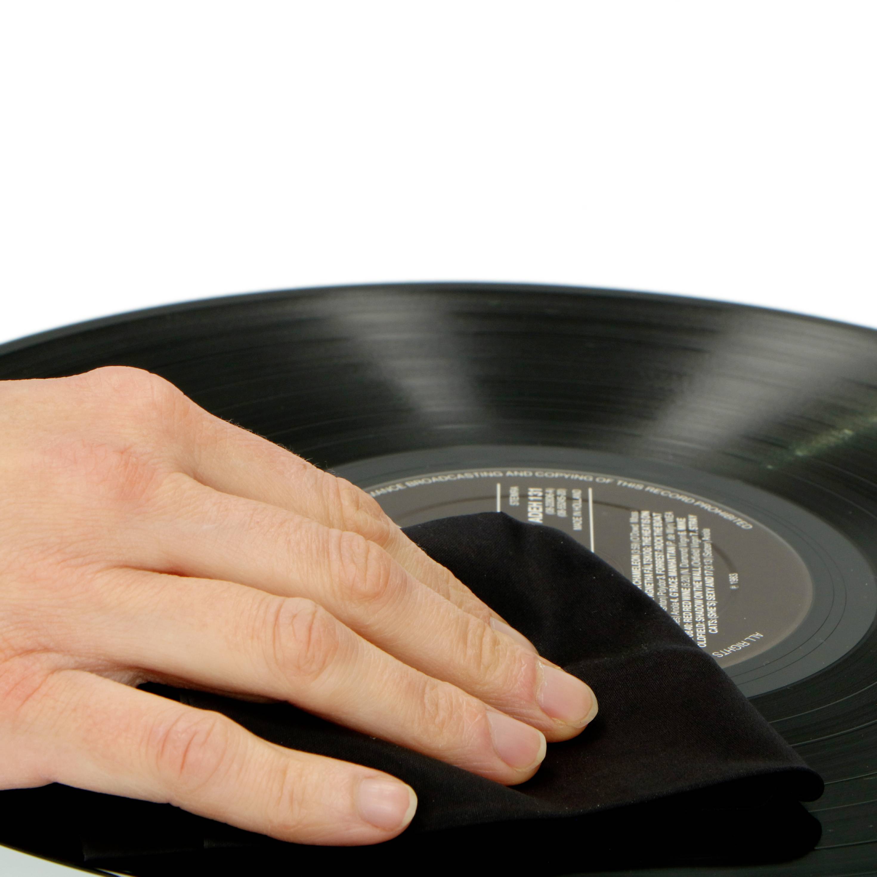'Primo piano di una mano che pulisce un disco in vinile con un panno.'