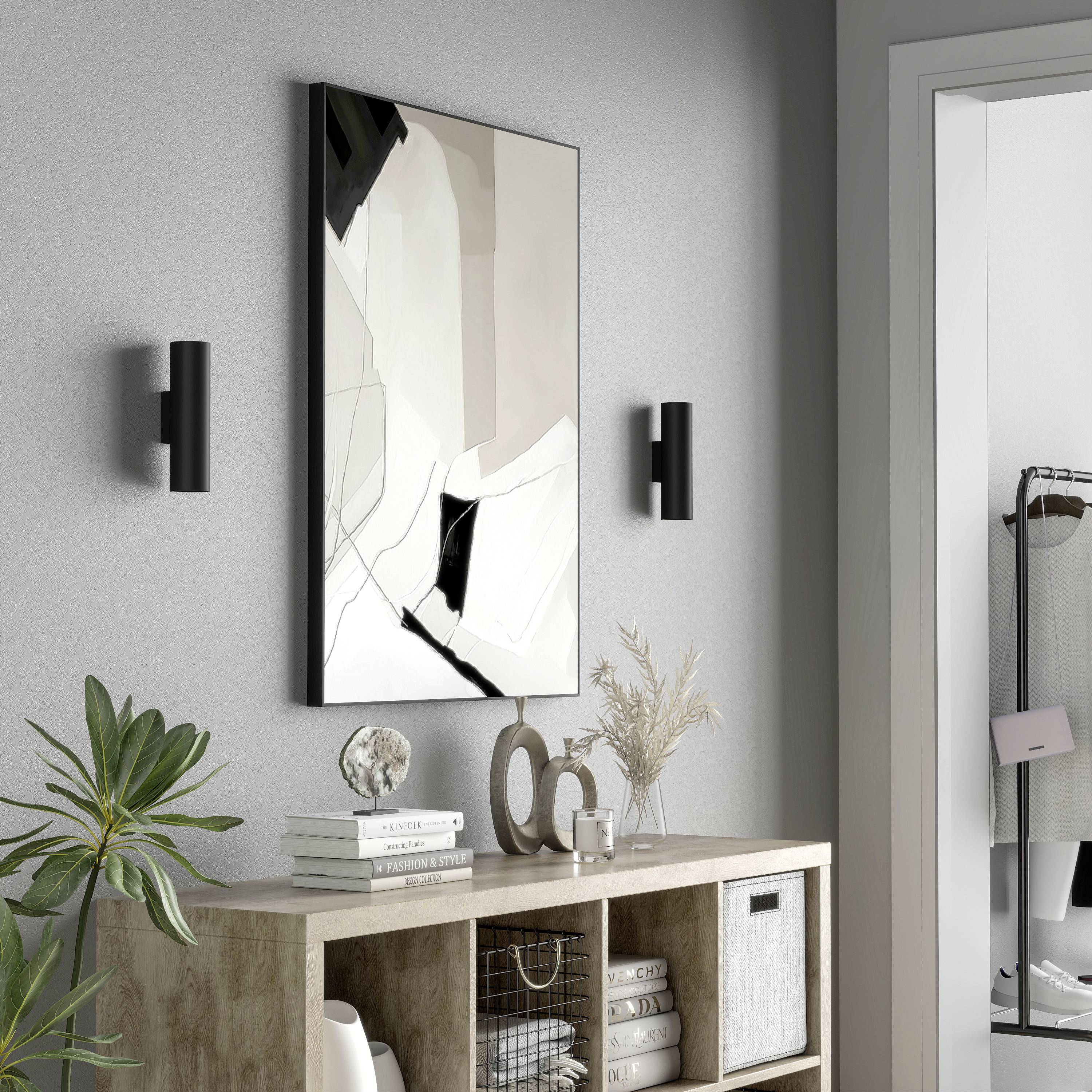 Soggiorno minimalista con mobili in legno chiaro, opera d'arte astratta, due applique da parete e decorazioni moderne, tra cui alcune piante.