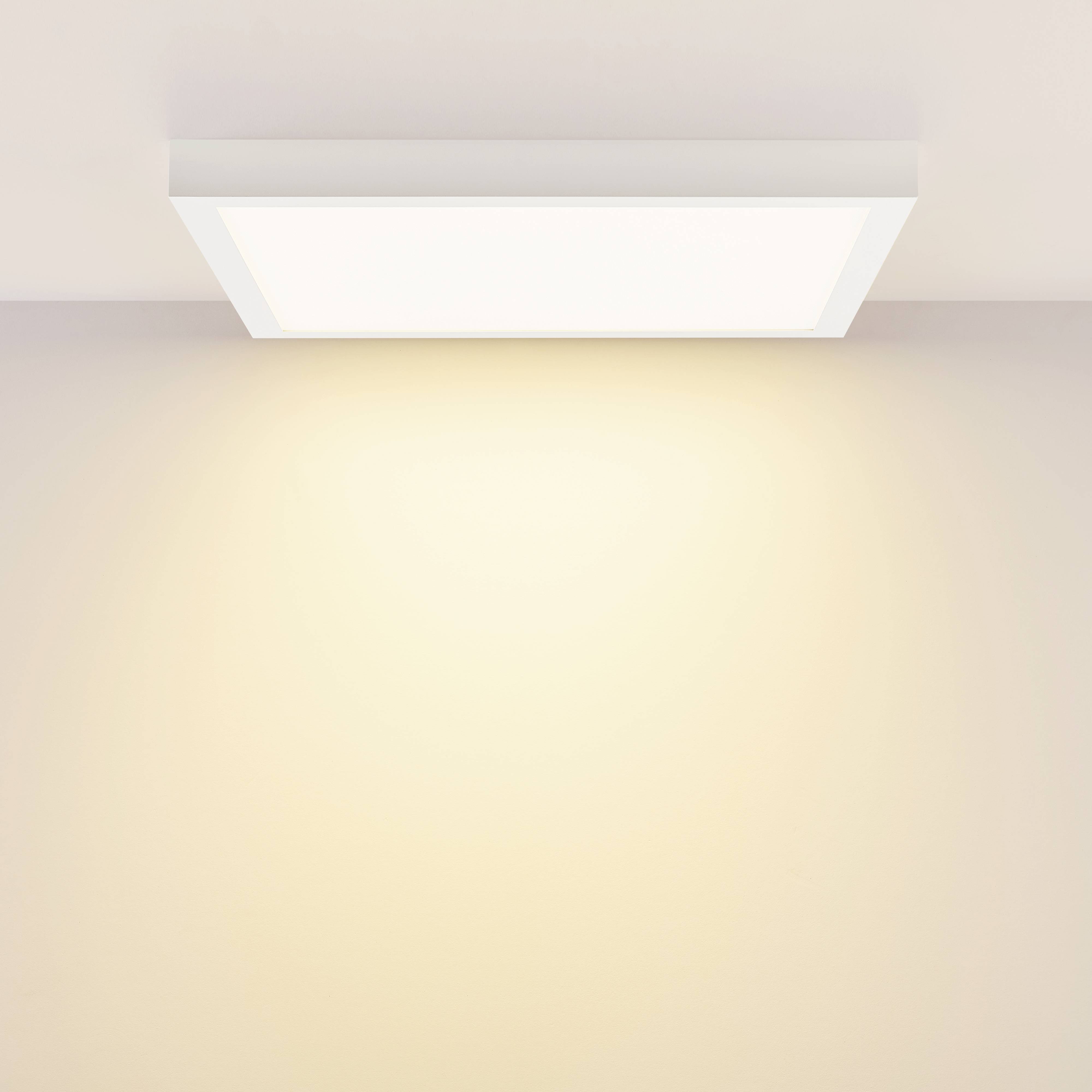 Una plafoniera quadrata emana una luce bianca calda uniforme, illuminando il soffitto bianco e la parete sottostante.