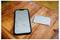Uno smartphone con un'app di mappe aperta è posizionato su un tavolo di legno accanto a una powerbank bianca.