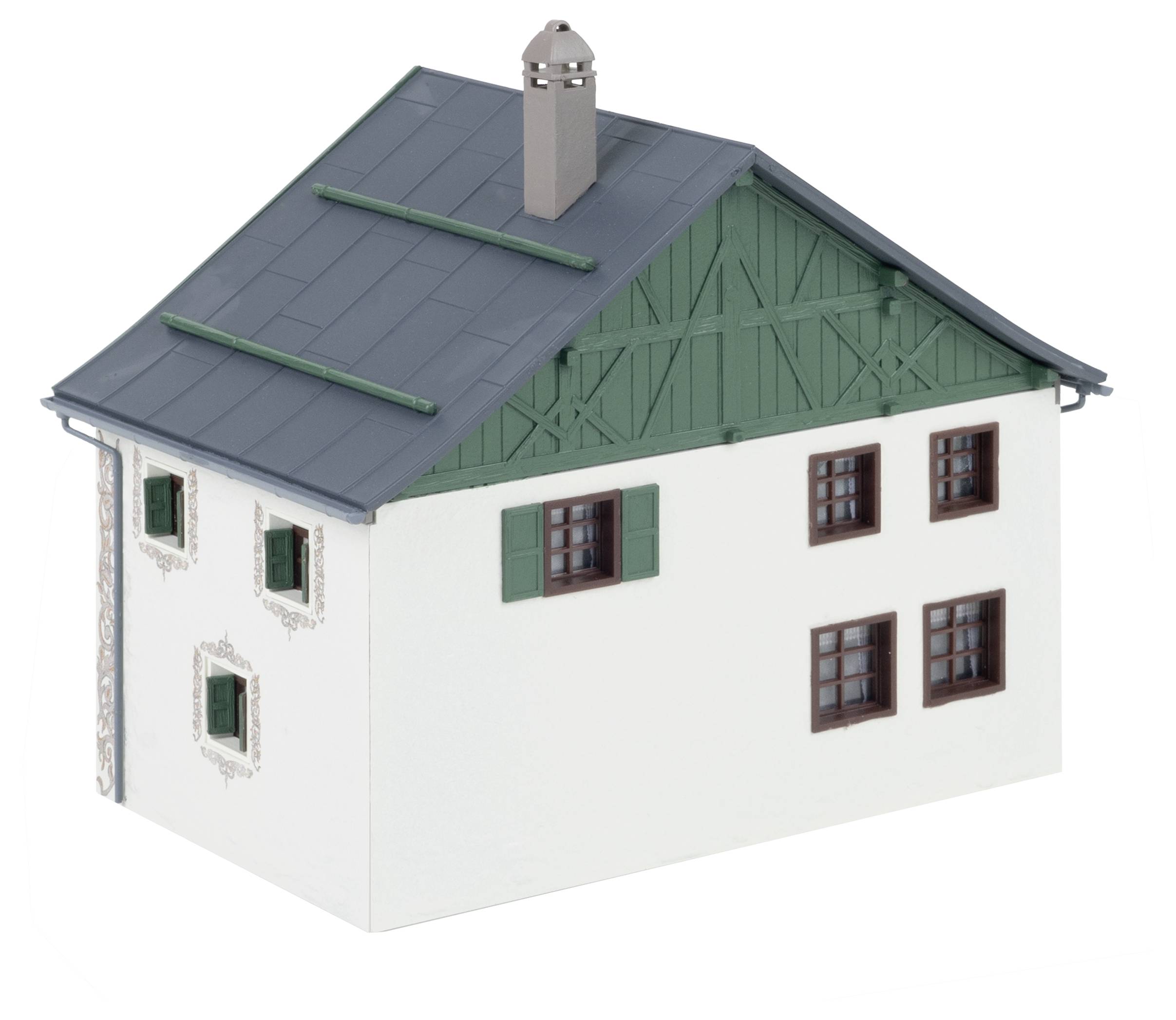 Una piccola casa modello con tetto grigio-verde e persiane verdi. Ha pareti bianche e un camino.