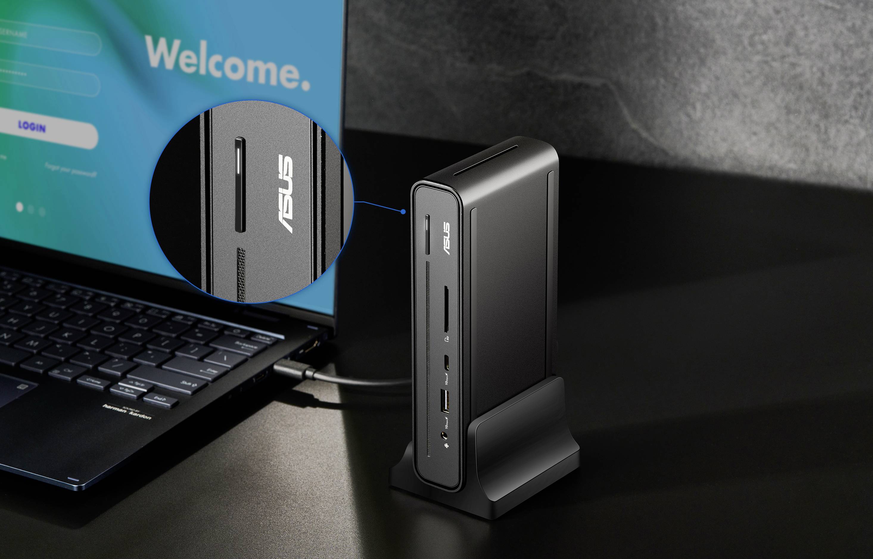 Una stazione di aggancio ASUS compatta e verticale collegata a un laptop. Lo schermo mostra un messaggio di 'Benvenuto', enfatizzando la connettività digitale.