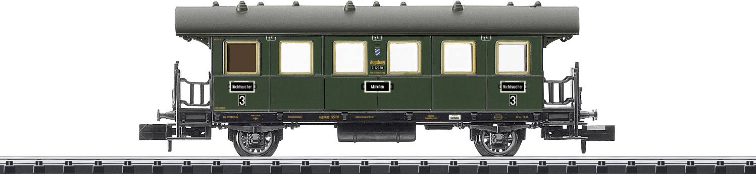 Un vagone verde per modellismo ferroviario sta viaggiando su un binario. Si tratta di un vagone passeggeri storico con dettagli classici.