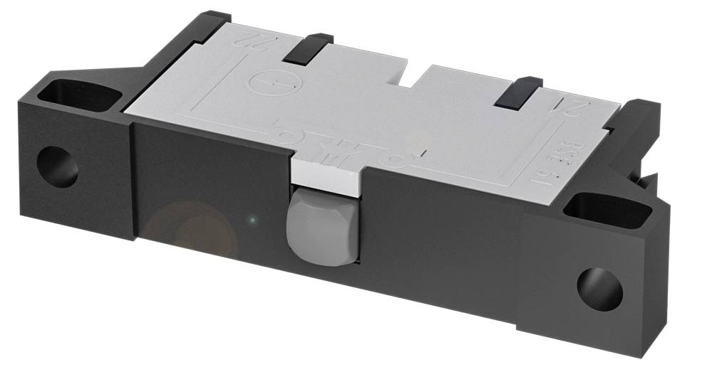 Un interruttore elettronico piatto rettangolare di colore nero e grigio, con due fori di fissaggio visibili su ciascun lato.