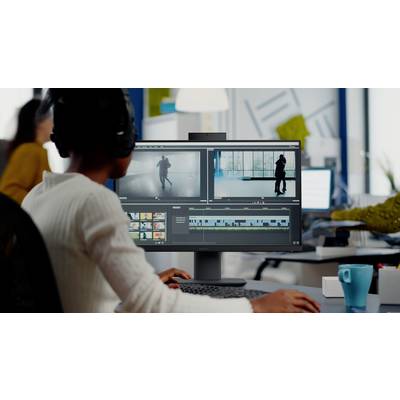 Una persona che modifica un video su uno schermo di computer con più clip e una timeline visibile in un ambiente di ufficio moderno.