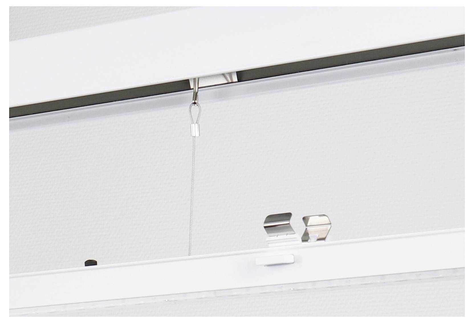 Primo piano di una tenda a rullo bianca da soffitto con cordino di comando e staffe metalliche montate in alto su una finestra.