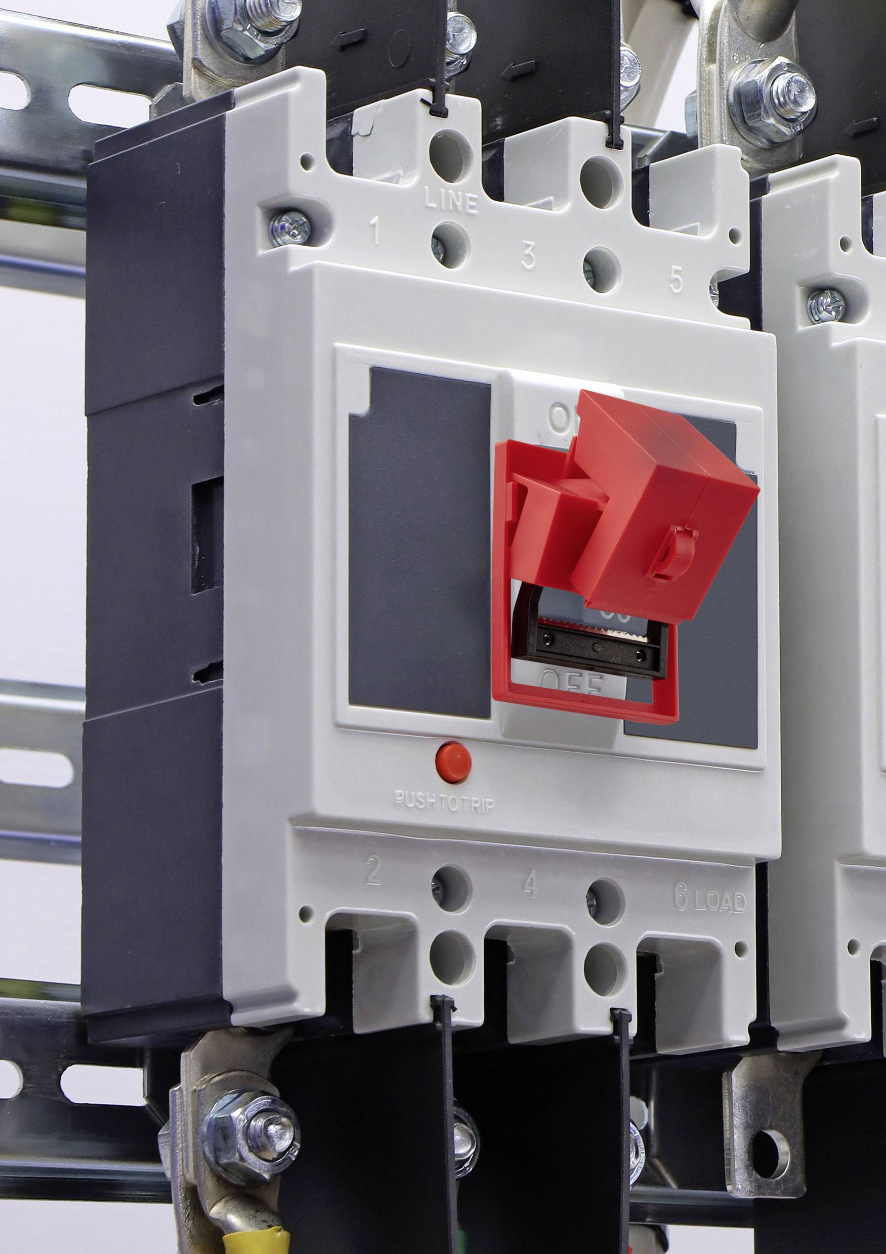 Un interruttore magnetotermico grigio e rosso montato su una guida metallica, con interruttori e punti di connessione etichettati 'LINEA' e 'CARICO'.
