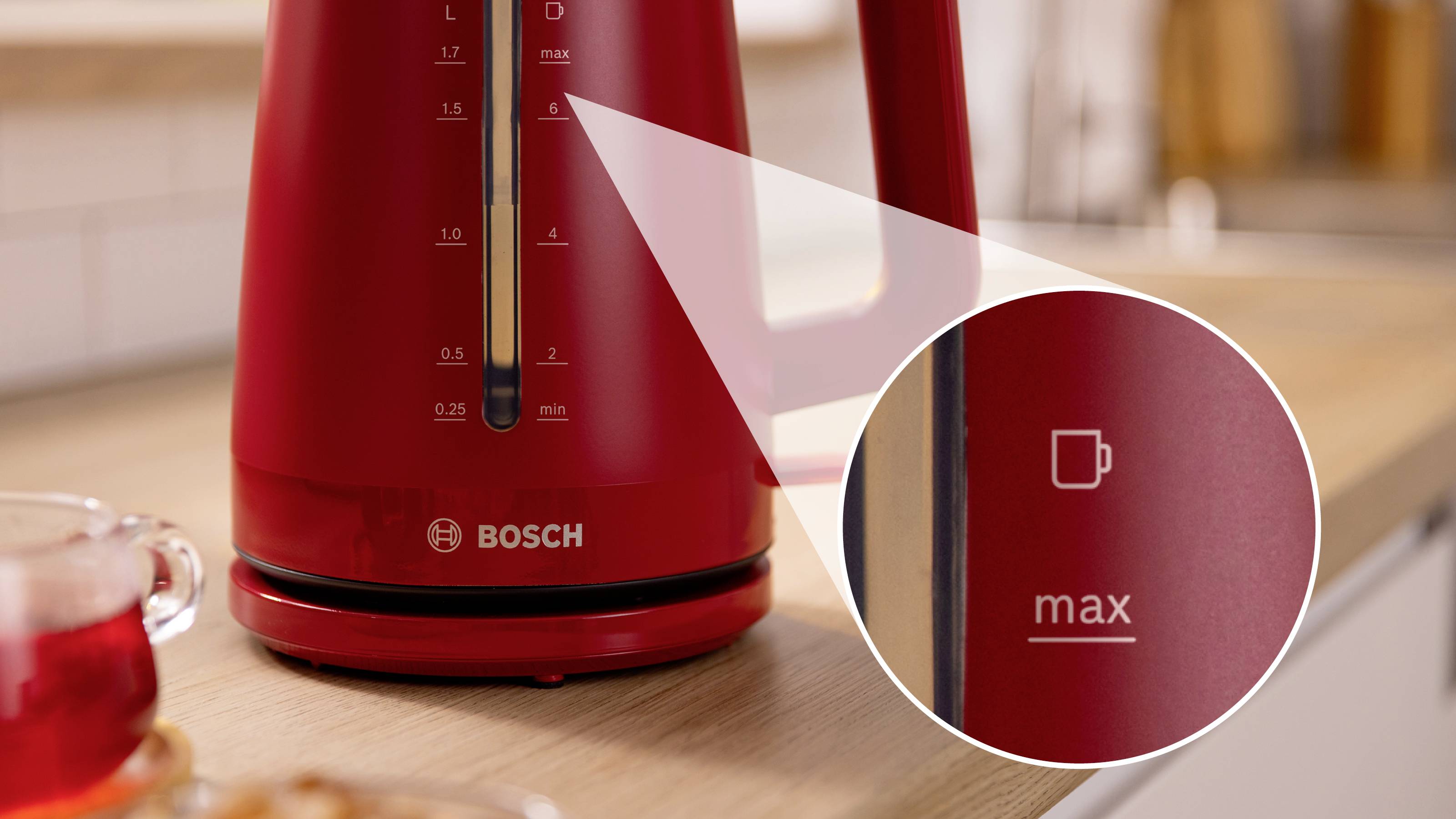 Bollitore elettrico rosso su un piano di lavoro della cucina, che mostra un primo piano dell'indicatore del livello massimo dell'acqua accanto a un simbolo di tazza.