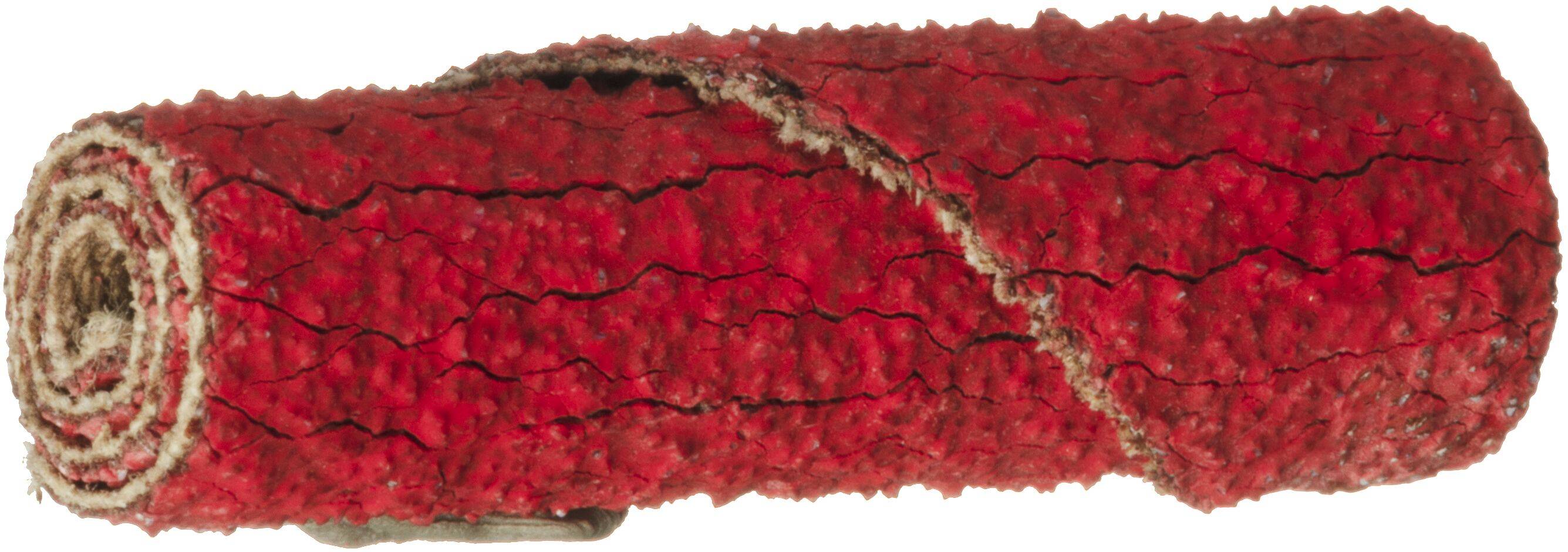 Un rotolo di tappeto rosso texturizzato con un bordo leggermente sfilacciato, che mostra un sottofondo beige.