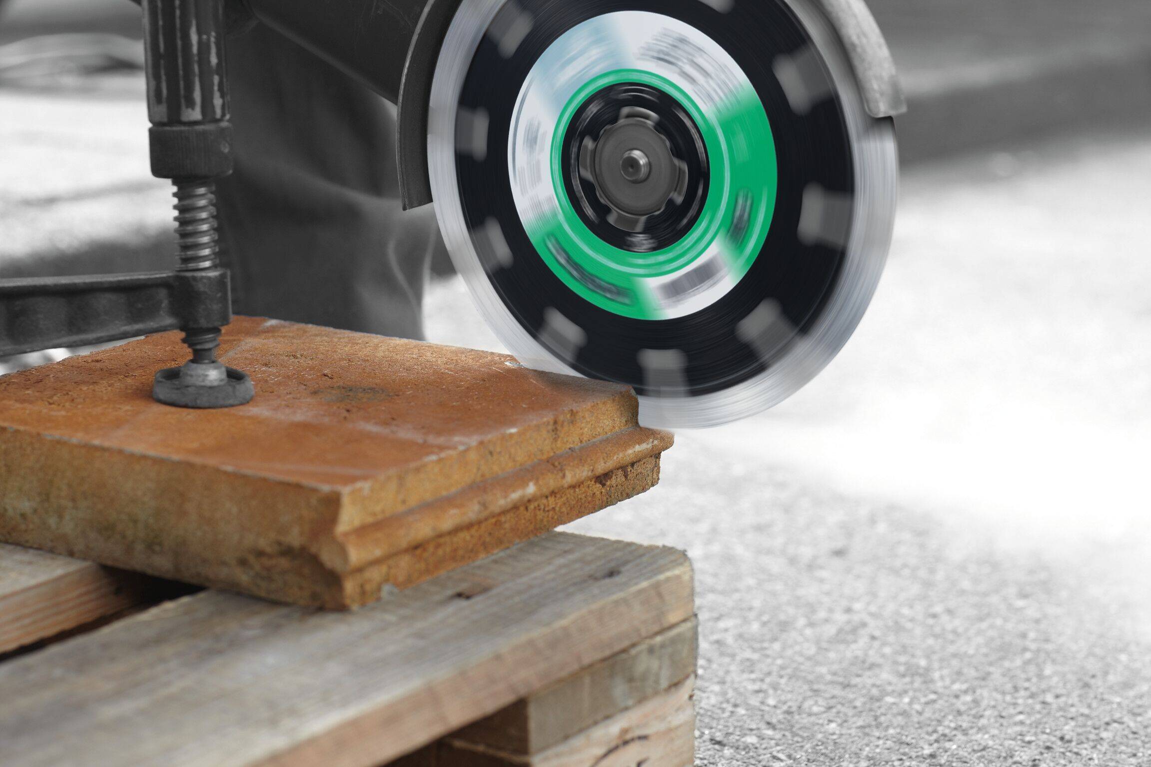 Un utensile da taglio in movimento che taglia attraverso un'asse di legno posizionata su un pallet, con una morsa che fissa l'asse.