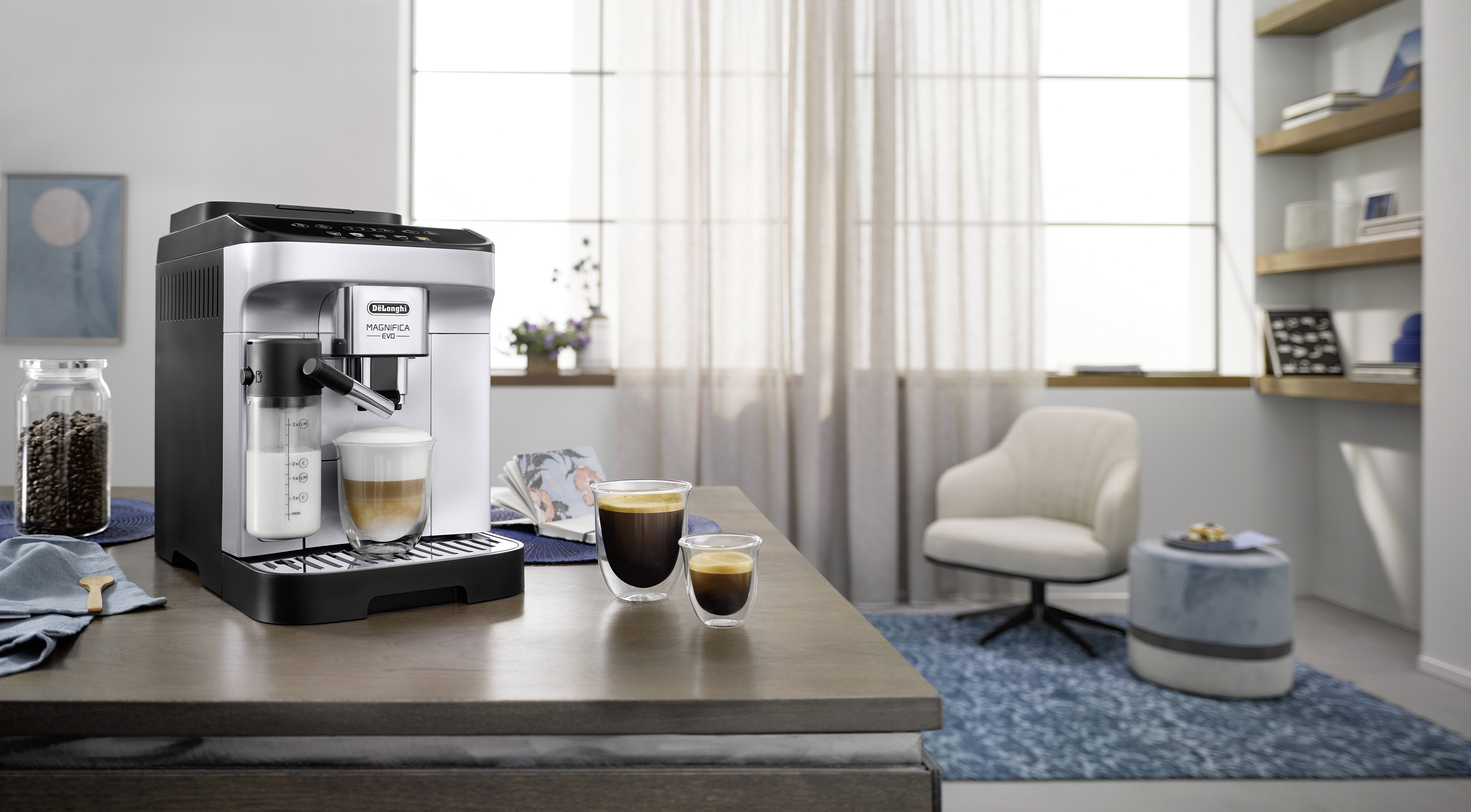 Una moderna macchina da caffè espresso su un piano di lavoro della cucina con due tazze di caffè fresche accanto, in un ambiente di cucina luminoso e accogliente.