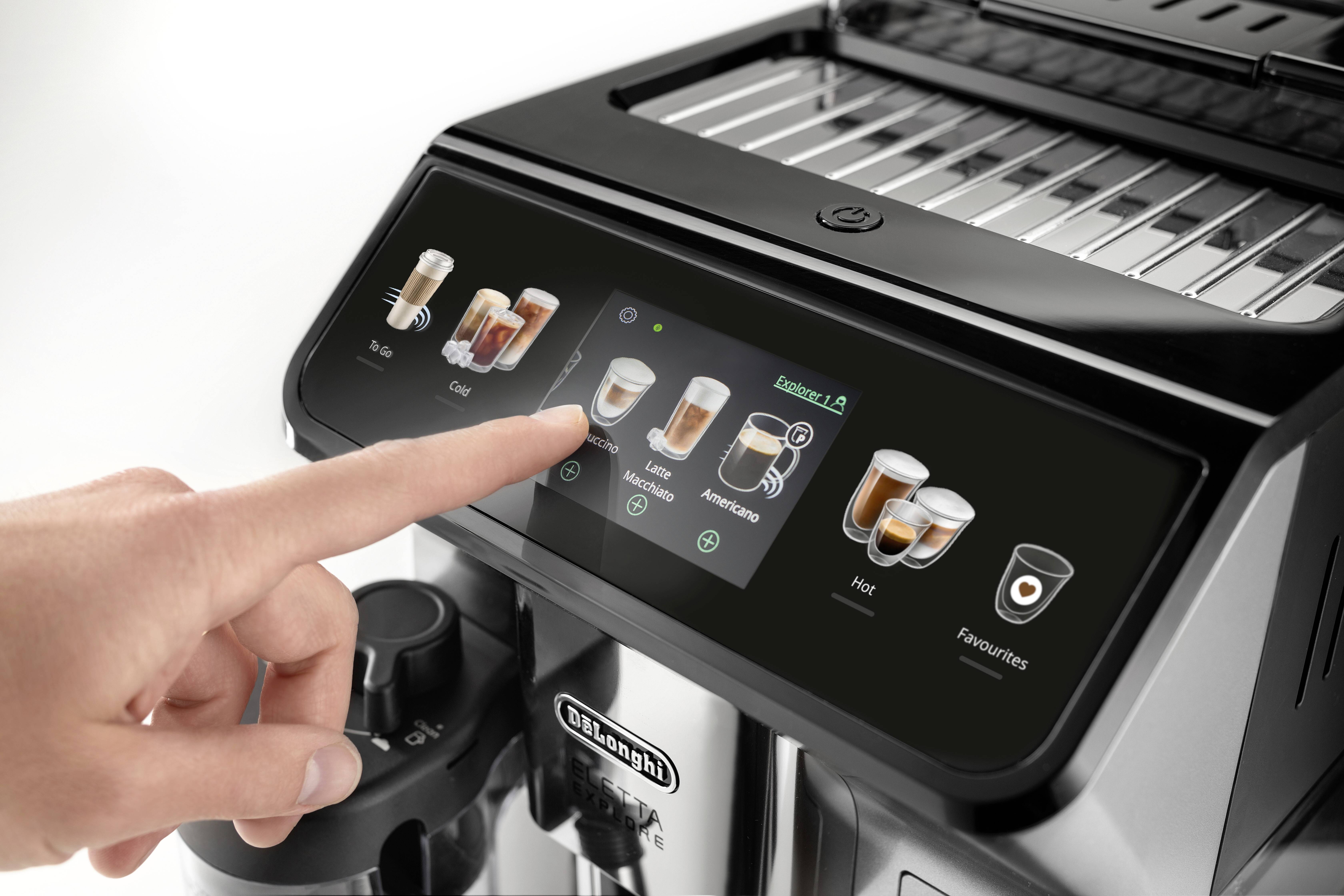 Un dito seleziona un'opzione di caffè sullo schermo touch di una macchina da caffè moderna. L'interfaccia mostra diversi tipi di caffè e impostazioni.