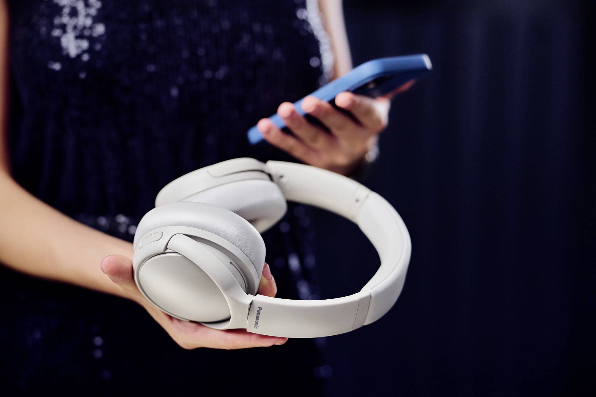 Una persona che tiene in mano uno smartphone e degli auricolari wireless, concentrata sulla tecnologia e sull'accessibilità musicale.