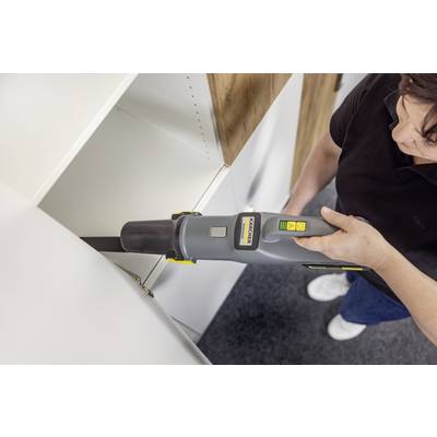 Una persona utilizza un aspirapolvere con un ugello stretto per pulire all'interno di un mobile bianco, illustrando una rimozione efficiente della polvere.